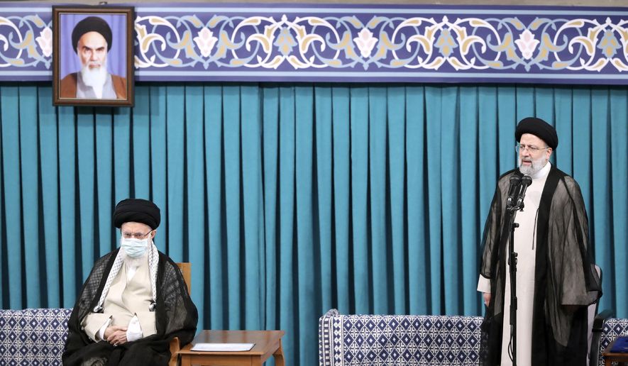 In this photo released by an official website of the office of the Iranian supreme leader, newly elected President Ebrahim Raisi, right, speaks after receiving official seal of approval of Supreme Leader Ayatollah Ali Khamenei, left, in an endorsement ceremony in Tehran, Iran, Tuesday, Aug. 3, 2021. A portrait of the late revolutionary founder Ayatollah Khomeini hangs at top left. (Office of the Iranian Supreme Leader via AP)