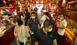 Visitors wear face masks to protect against COVID-19 as they walk at a tourist shopping street in Beijing, Tuesday, Aug. 3, 2021. Chinese authorities announced Tuesday mass coronavirus testing in Wuhan as an unusually wide series of COVID-19 outbreaks reached the city where the disease was first detected in late 2019. The current outbreaks, while still in the hundreds of cases in total, have spread much more widely than previous ones, reaching multiple provinces and cities including the capital, Beijing. (AP Photo/Mark Schiefelbein)