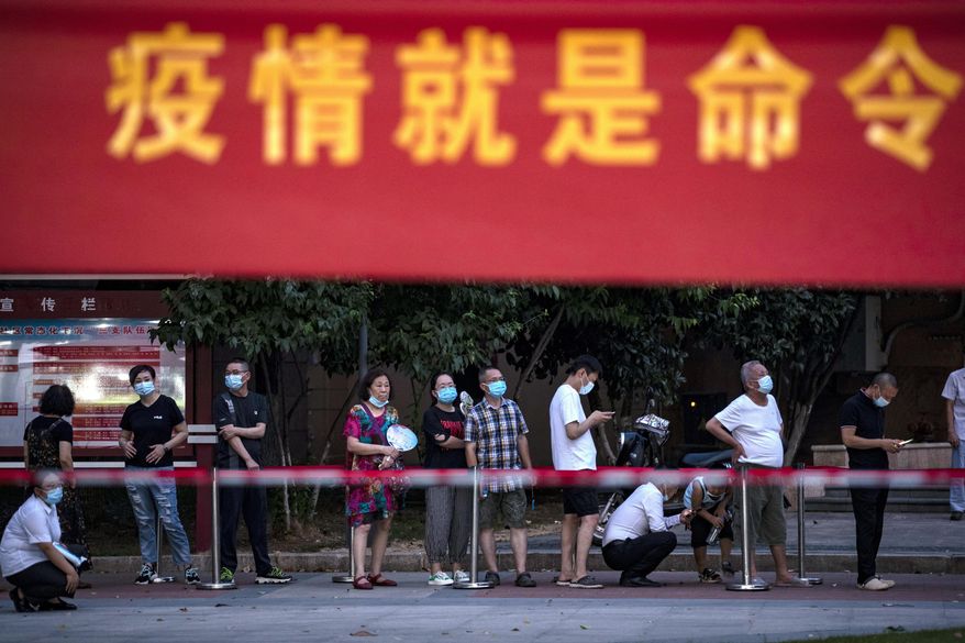 In this file photo, residents line up for Covid-19 tests near a banner with the words &#x27;Epidemic is the Order&#x27; in Wuhan in central China&#x27;s Hubei province Tuesday, Aug. 3, 2021. China&#x27;s worst coronavirus outbreak since the start of the pandemic a year and a half ago escalated Wednesday with dozens more cases around the country, the sealing-off of one city and the punishment of its local leaders. (Chinatopix Via AP)  **FILE**