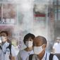 People wearing face masks to protect against the spread of the coronavirus walk under a water mist in Tokyo Thursday, Aug. 5, 2021. New cases surge in Tokyo to record levels during the Olympic Games. (AP Photo/Koji Sasahara)