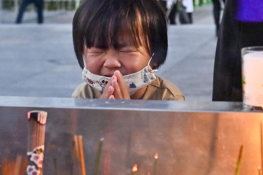 A child prays in front of the cenotaph dedicated to the victims of the atomic bombing at the Hiroshima Peace Memorial Park in Hiroshima, western Japan Friday, Aug. 6, 2021. Hiroshima on Friday marked the 76th anniversary of the world&#x27;s first atomic bombing of the city. (Kyodo News via AP)