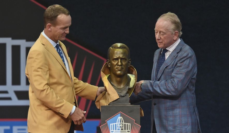 Peyton Manning, left, a member of the Pro Football Hall of Fame Class of 2021, and his presenter and father Archie Manning unveil a bust of Peyton during the induction ceremony at the Pro Football Hall of Fame, Sunday, Aug. 8, 2021, in Canton, Ohio. (AP Photo/David Richard)