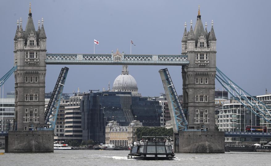A boat sails down the River Thames in London, Monday Aug. 9, 2021 in front of Tower Bridge that is stuck in the fully open position due to a technical fault. (AP Photo/Tony Hicks)