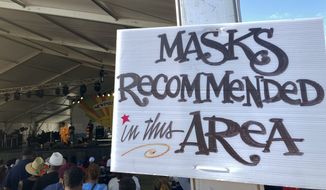 In this July 31, 2021, file photo, a sign recommends attendees of the Newport Jazz Festival wear masks in a tented area where singer Ledisi performs in Newport, R.I. Festival-goers were also required to digitally upload proof of COVID-19 vaccination or a recent negative test. (AP Photo/Matt O&#39;Brien, File)