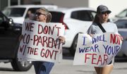 In this file photo, two women display signs as they cross the street during a protest outside a Broward County School Board meeting, Tuesday, Aug. 10, 2021, in Fort Lauderdale, Fla., to discuss a possible mask mandate when school starts next week. From mask mandates to Critical Race Theory to LGBT reading materials, issues surrounding public education have sprung to the top of the agenda at the February 2022 gathering of CPAC, the nation’s most influential gathering of conservatives. (Amy Beth Bennett/South Florida Sun-Sentinel via AP)  **FILE**