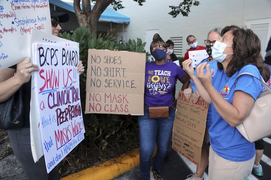 Yvonne Moniz, right, a special needs teacher at Challenger Elementary, along with Oakland Park Elementary third grade teacher Donna Sacco, second from right, and Oriole Elementary fourth grade teacher Yolanda Smith, center, tries to persuade anti-mask protester Heather Tanner that all students need to wear masks to protect the most vulnerable. during a protest outside of a Broward County School Board meeting, Tuesday, Aug. 10, 2021, in in Fort Lauderdale, Fla., to discuss a possible mask mandate when school starts next week. (Amy Beth Bennett/South Florida Sun-Sentinel via AP)