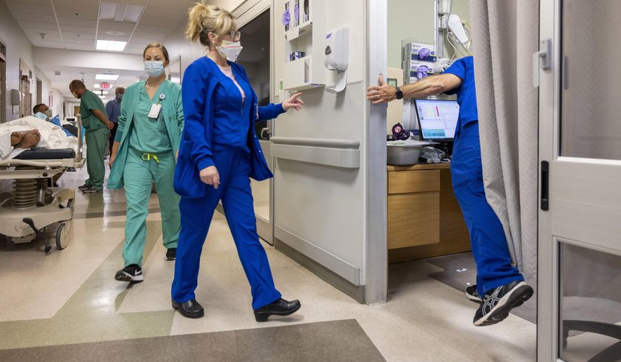 Running from room to room, emergency room director Mark Kellar, right, hurries between patients at Our Lady of Angels Hospital in Bogalusa, La., Monday, Aug. 9, 2021. (Chris Granger/The Advocate via AP)