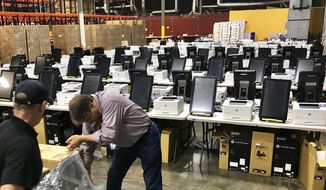 FILE - This Feb. 14, 2020, file photos shows voting equipment including touchscreen tablet, printer and scanner in a metro Atlanta warehouse, to be tested before shipped to Georgia counties. (AP Photo/Jeff Martin, File)