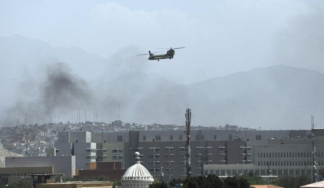 A U.S. Chinook helicopter flies over the city of Kabul, Afghanistan, Sunday, Aug. 15, 2021. Taliban fighters entered the outskirts of the Afghan capital on Sunday, further tightening their grip on the country as panicked workers fled government offices and helicopters landed at the U.S. Embassy. (AP Photo/Rahmat Gul)