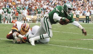 Philadelphia Eagles quarterback Randall Cunningham (12) is tripped up by Washington Redskins&#39; linebacker Rich Milot (57) in first half action at RFK Stadium, Sept. 22, 1985. (AP Photo/Dennis Cook) **FILE**