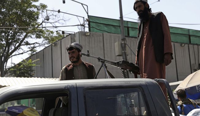 Taliban fighters stand guard on the back of vehicle with a machine gun in front of main gate leading to Afghan presidential palace, in Kabul, Afghanistan, Monday, Aug. 16, 2021. The U.S. military has taken over Afghanistan&#x27;s airspace as it struggles to manage a chaotic evacuation after the Taliban rolled into the capital. (AP Photo/Rahmat Gul)