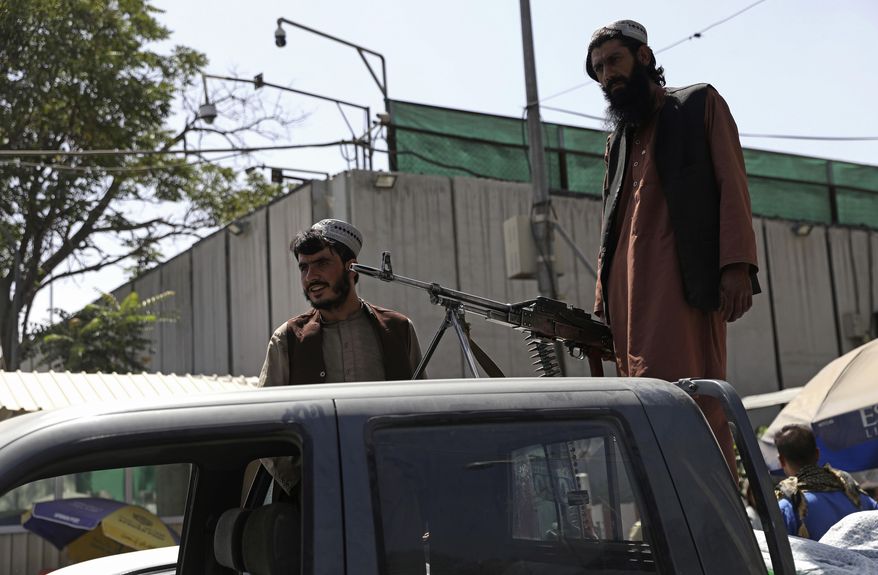 Taliban fighters stand guard on the back of vehicle with a machine gun in front of main gate leading to Afghan presidential palace, in Kabul, Afghanistan, Monday, Aug. 16, 2021. The U.S. military has taken over Afghanistan&#x27;s airspace as it struggles to manage a chaotic evacuation after the Taliban rolled into the capital. (AP Photo/Rahmat Gul)