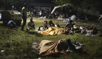 People displaced from their earthquake destroyed homes spend the night outdoors in a grassy area that is part of a hospital in Les Cayes, Haiti, late Saturday, Aug. 14, 2021. A powerful magnitude 7.2 earthquake struck southwestern Haiti on Saturday. (AP Photo/Joseph Odelyn)