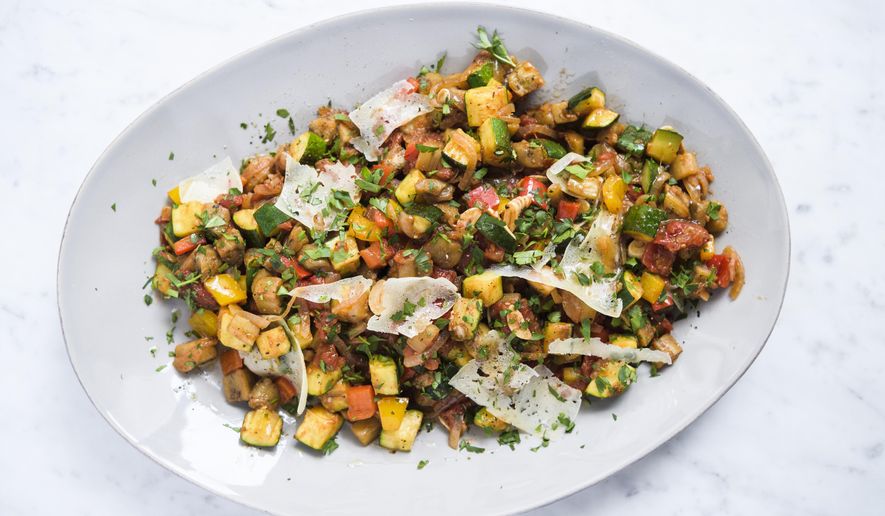 This image released by Milk Street shows a recipe for Spanish ratatouille, a combination of sautéed summer vegetables with shaved curls of manchego cheese. (Milk Street via AP)