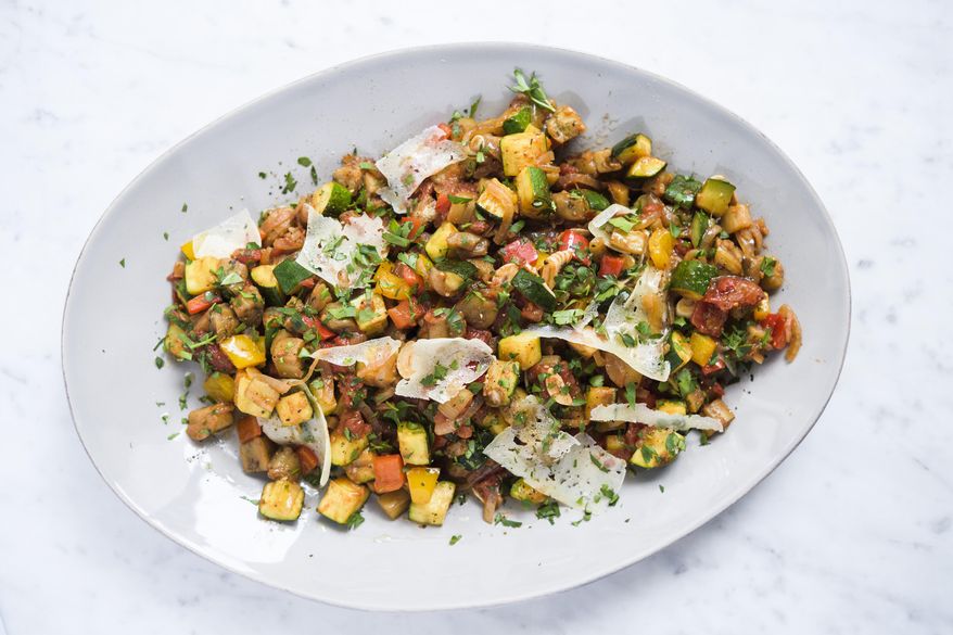 This image released by Milk Street shows a recipe for Spanish ratatouille, a combination of sautéed summer vegetables with shaved curls of manchego cheese. (Milk Street via AP)