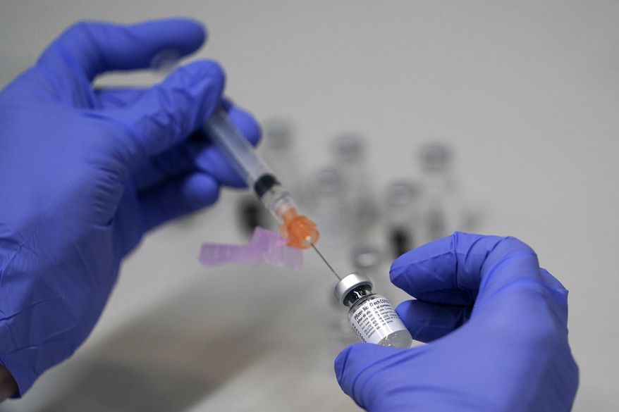 A pharmacy technician loads a syringe with Pfizer's COVID-19 vaccine, Tuesday, March 2, 2021, at a mass vaccination site at the Portland Expo in Portland, Maine. (AP Photo/Robert F. Bukaty) ** FILE **