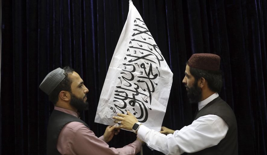 Taliban officials arrange a Taliban flag, before a press conference by Taliban spokesman Zabihullah Mujahid, at the Government Media Information Center, in Kabul, Afghanistan, Tuesday, Aug. 17, 2021. Mujahid vowed Tuesday that the Taliban would respect women&#39;s rights, forgive those who resisted them and ensure a secure Afghanistan as part of a publicity blitz aimed at convincing world powers and a fearful population that they have changed. (AP Photo/Rahmat Gul)