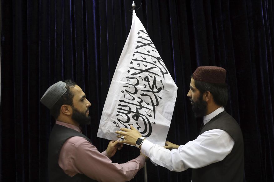 Taliban officials arrange a Taliban flag, before a press conference by Taliban spokesman Zabihullah Mujahid, at the Government Media Information Center, in Kabul, Afghanistan, Tuesday, Aug. 17, 2021. Mujahid vowed Tuesday that the Taliban would respect women&#39;s rights, forgive those who resisted them and ensure a secure Afghanistan as part of a publicity blitz aimed at convincing world powers and a fearful population that they have changed. (AP Photo/Rahmat Gul)