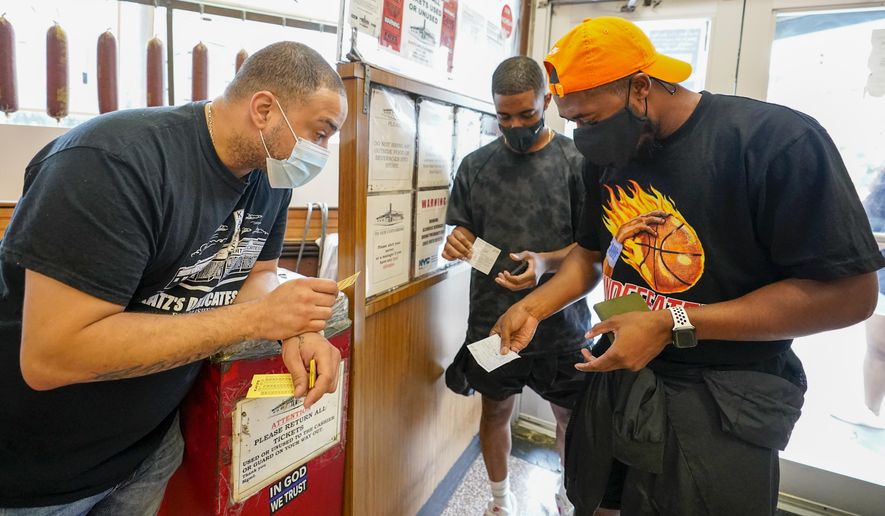 A Katz&#39;s Deli employee, left, checks the proof of vaccination from customers who will be eating inside the restaurant, Tuesday, Aug. 17, 2021, in New York. New York City is asking restaurants, gyms, museums and many other indoor venues to have patrons show proof of vaccination against COVID-19. The new rules are part of the city&#39;s latest campaign to control a pandemic that had crippled the city&#39;s economy. (AP Photo/Mary Altaffer)