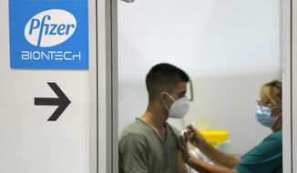 A medical worker administers a shot of Pfizer COVID-19 vaccine to a man at Belgrade Fair makeshift vaccination center in Belgrade, Serbia, Tuesday, Aug. 17, 2021.  Serbia has started administering a third, or booster, dose of four different vaccines, including Sinopharm, Pfizer, Sputnik and AstraZeneca, to people who previously were vaccinated at least 6 months ago.  (AP Photo/Darko Vojinovic)
