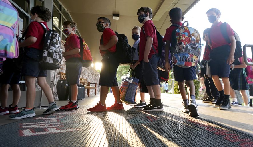 Wearing masks to prevent the spread of COVID-19, elementary school students line up to enter school for the first day of classes in Richardson, Texas, Tuesday, Aug. 17, 2021. Despite Texas Gov. Greg Abbott&#39;s executive order banning mask mandates by local officials, the Richardson Independent School District and many others across the state are requiring masks for students. (AP Photo/LM Otero)
