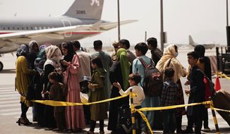 In this photo provided by the U.S. Marine Corps, civilians prepare to board a plane during an evacuation at Hamid Karzai International Airport, Kabul, Afghanistan, Wednesday, Aug. 18, 2021. (Staff Sgt. Victor Mancilla/U.S. Marine Corps  via AP)