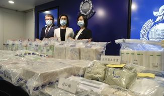 Ng Wing-sze, center, acting chief superintendent Narcotics Bureau, and two senior police officials pose with the seized cocaine during a news conference in Hong Kong Thursday, Aug. 19, 2021. Hong Kong police said Thursday that they seized 195 million Hong Kong dollars ($25 million) worth of illegal drugs as part of a monthslong investigation, the largest seizure of the year. (AP Photo/Vincent Yu)