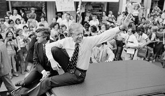 FILE - In this July 31, 1979, file photo, President Jimmy Carter waves from the roof of his car along the parade route through Bardstown, Ky. Carter is sometimes called a better former president than he was president. The backhanded compliment has always rankled Carter allies and, they say, the former president himself. Yet now, 40 years removed from the White House, the most famous resident of Plains, Georgia, is riding a new wave of attention as biographers, filmmakers, climate activists and Carter’s fellow Democrats push for a recasting of his presidential legacy. (AP Photo/Bob Daugherty, FIle)