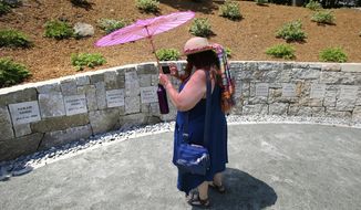FILE - In this July 19, 2017, file photograph, Karla Hailer, a fifth-grade teacher from Scituate, Mass., shoots a video where a memorial stands at the site in Salem, Mass., where five women were hanged as witches more than 325 years earlier. A woman convicted of witchcraft in 1693 and sentenced to death at the height of the Salem Witch Trials finally will be exonerated if Massachusetts lawmakers approve a bill inspired by a curious eighth-grade history class. State Sen. Diana DiZoglio, a Democrat from Methuen, has introduced legislation to clear the name of Elizabeth Johnson Jr., 328 years after she was condemned but never executed. DiZoglio says she was inspired by sleuthing done by a group of 13- and 14-year-olds at North Andover Middle School. (AP Photo/Stephan Savoia, File)