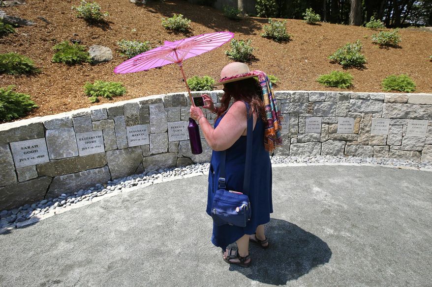 FILE - In this July 19, 2017, file photograph, Karla Hailer, a fifth-grade teacher from Scituate, Mass., shoots a video where a memorial stands at the site in Salem, Mass., where five women were hanged as witches more than 325 years earlier. A woman convicted of witchcraft in 1693 and sentenced to death at the height of the Salem Witch Trials finally will be exonerated if Massachusetts lawmakers approve a bill inspired by a curious eighth-grade history class. State Sen. Diana DiZoglio, a Democrat from Methuen, has introduced legislation to clear the name of Elizabeth Johnson Jr., 328 years after she was condemned but never executed. DiZoglio says she was inspired by sleuthing done by a group of 13- and 14-year-olds at North Andover Middle School. (AP Photo/Stephan Savoia, File)
