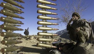 Afghan anti-al-Qaeda fighters rest at a former al Qaeda base in the White Mountains near Tora Bora on Wednesday, Dec. 19, 2001, behind a string of ammunition found after the retreat of al-Qaida members from the area. (AP Photo/David Guttenfelder) ** FILE **