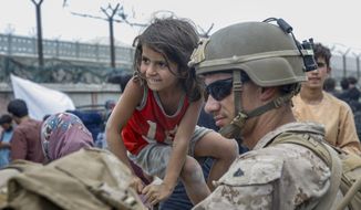 In this image provided by the U.S. Marines, a Marine with Special Purpose Marine Air-Ground Task Force - Crisis Response - Central Command, waits with a child during an evacuation at Hamid Karzai International Airport in Kabul, Afghanistan, Friday, Aug. 20, 2021. (Lance Cpl. Nicholas Guevara/U.S. Marine Corps via AP)
