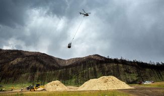 In this Friday, Aug. 6, 2021 photo, a helicopter picks up mulch to spread in Poudre Canyon, about 50 miles west of Fort Collins, to try to stem silt runoff during large rains near Red Feather Lakes, Colo. (Kevin J. Beaty/Colorado Public Radio via AP)