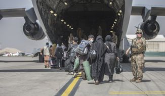 In this image provided by the U.S. Marine Corps, families begin to board a U.S. Air Force Boeing C-17 Globemaster III during an evacuation at Hamid Karzai International Airport in Kabul, Afghanistan, Monday, Aug. 23, 2021. (Sgt. Samuel Ruiz/U.S. Marine Corps via AP)