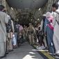 In this Aug. 21, 2021, image provided by the U.S. Air Force, U.S. Airmen and U.S. Marines guide evacuees aboard a U.S. Air Force C-17 Globemaster III in support of the Afghanistan evacuation at Hamid Karzai International Airport in Kabul, Afghanistan. (Senior Airman Brennen Lege/U.S. Air Force via AP) ** FILE **