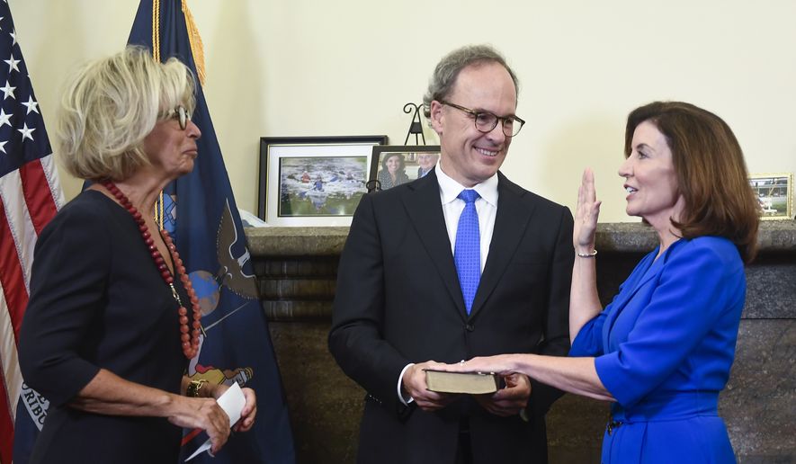 New York Chief Judge Janet DiFiore, left, swears in Kathy Hochul, right, as the first woman to be New York&#39;s governor while her husband Bill Hochul holds a bible during a swearing-in ceremony in the Red Room at the state Capitol, early Tuesday, Aug. 24, 2021, in Albany, N.Y. (AP Photo/Hans Pennink, Pool)