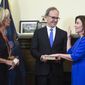 New York Chief Judge Janet DiFiore, left, swears in Kathy Hochul, right, as the first woman to be New York&#39;s governor while her husband Bill Hochul holds a bible during a swearing-in ceremony in the Red Room at the state Capitol, early Tuesday, Aug. 24, 2021, in Albany, N.Y. (AP Photo/Hans Pennink, Pool)
