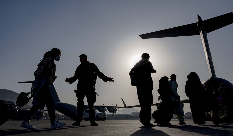 In this image provided by the U.S. Air Force, U.S. Air Force Airmen guides evacuees aboard a U.S. Air Force C-17 Globemaster III at Hamid Karzai International Airport in Kabul, Afghanistan, Tuesday, Aug. 24, 2021. (Senior Airman Taylor Crul/U.S. Air Force via AP)