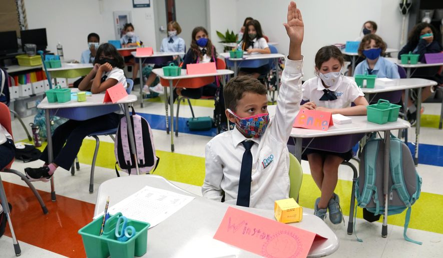 Student Winston Wallace, 9, raises his hand in class at iPrep Academy on the first day of school, Monday, Aug. 23, 2021, in Miami. Schools in Miami-Dade County opened Monday with a strict mask mandate to guard against coronavirus infections. (AP Photo/Lynne Sladky)