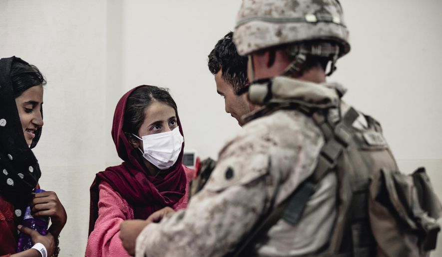 In this image provided by the U.S. Marine Corps, a Marine processes youth to be evacuated, at Hamid Karzai International Airport, Monday, Aug. 23. (Gunnery Sgt. Melissa Marnell/U.S. Marine Corps via AP)