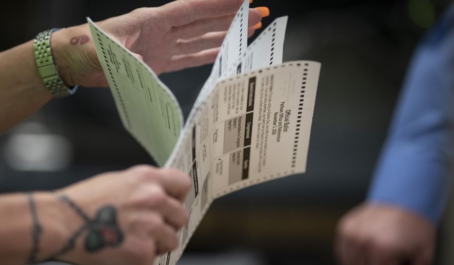 FILE - In this Nov. 3, 2020, file photo, poll workers sort out early and absentee ballots at the Kenosha Municipal building on Election Day in Kenosha, Wis. A federal report from July 2021 finds that in the run up to the 2020 presidential election, U.S. states and territories had spent less than a third of the $805 million Congress had provided to shore up security for state and local election systems. (AP Photo/Wong Maye-E, File)