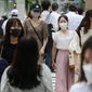 People wearing face masks to help protect against the spread of the coronavirus walk across an intersection Tuesday, Aug. 24, 2021. (AP Photo/Koji Sasahara)