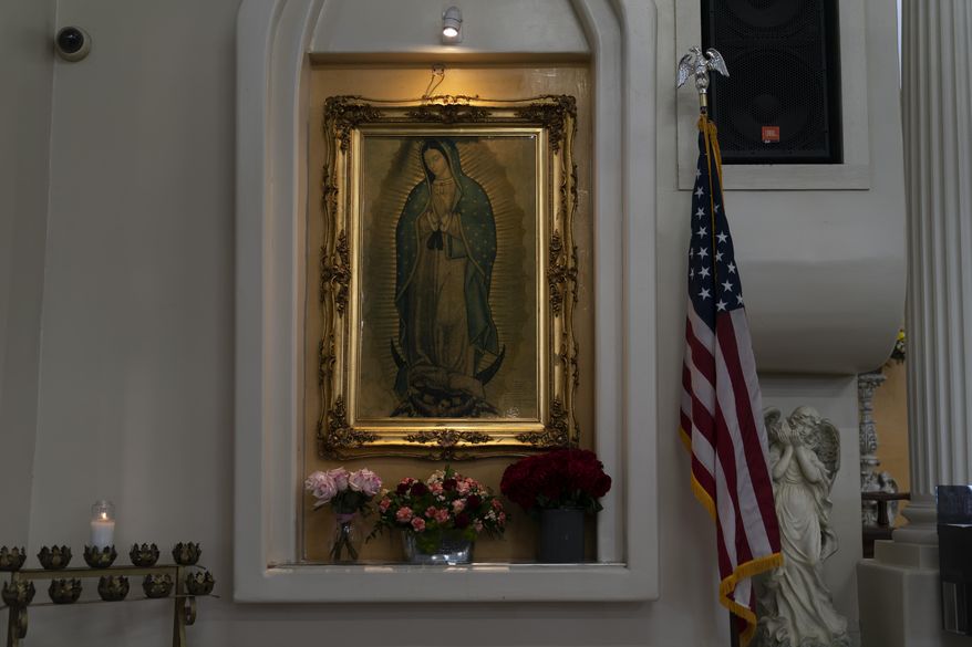 An America flag stands next to a portrait of Our Lady of Guadalupe at Immaculate Heart of Mary Catholic Church Friday, Aug. 20, 2021, in Somerton, Ariz. (AP Photo/Jae C. Hong)