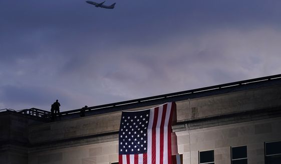 In this Friday, Sept. 11, 2020, file photo, a plane takes off from Washington Reagan National Airport as a large U.S. flag is unfurled at the Pentagon ahead of ceremonies at the National 9/11 Pentagon Memorial to honor the 184 people killed in the 2001 terrorist attack on the Pentagon, in Washington, Friday, Sept. 11, 2020. (AP Photo/J. Scott Applewhite, File)  ** FILE **