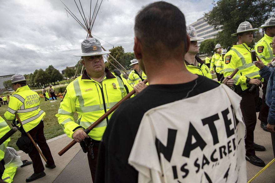 Minnesota State Troopers face off with environmental activists, who identify as water protectors, at the Minnesota State Capitol after activists opposing the Line 3 oil pipeline occupied the site overnight in St. Paul, Minn., Friday, Aug. 27, 2021. (Evan Frost/Minnesota Public Radio via AP)