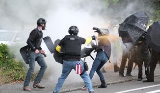 This Sunday, Aug. 22, 2021, file photo, members of the far-right group Proud Boys and anti-fascist protesters spray bear mace at each other during clashes between the politically opposed groups in Portland, Ore.  Police in Portland have been criticized that they did little to prevent violent clashes between right- and left-wing protesters on Sunday.  (AP Photo/Alex Milan Tracy)