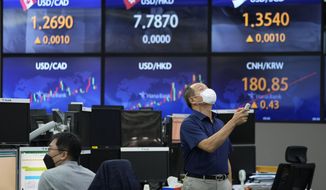 A currency trader uses a remote control to adjust temperature on an overhead air-conditioner at the foreign exchange dealing room of the KEB Hana Bank headquarters in Seoul, South Korea, Friday, Aug. 27, 2021. Asian stock markets were mixed Friday as investors awaited more guidance on the U.S. Federal Reserve&#39;s easing plans. (AP Photo/Ahn Young-joon)