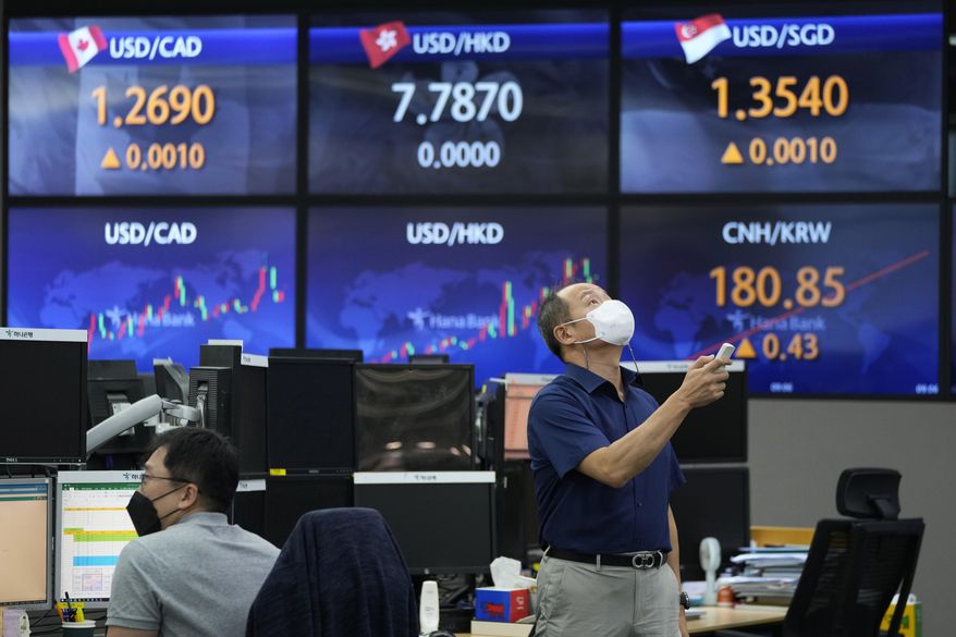 A currency trader uses a remote control to adjust temperature on an overhead air-conditioner at the foreign exchange dealing room of the KEB Hana Bank headquarters in Seoul, South Korea, Friday, Aug. 27, 2021. Asian stock markets were mixed Friday as investors awaited more guidance on the U.S. Federal Reserve&#39;s easing plans. (AP Photo/Ahn Young-joon)