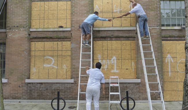 A crew covers windows along Julia St. in the Central Business District as Hurricane Ida approaches the Louisiana coast in New Orleans, La. Saturday, Aug. 28, 2021.  Residents across Louisiana’s coast rushed to prepare for the approach of an intensifying Hurricane Ida. The storm is expected to bring winds as high as 140 mph when it slams ashore late Sunday.( Max Becherer, NOLA.com, The Times-Picayune/The New Orleans Advocate via AP)