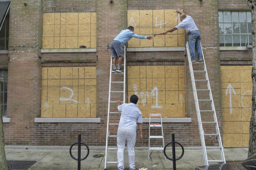A crew covers windows along Julia St. in the Central Business District as Hurricane Ida approaches the Louisiana coast in New Orleans, La. Saturday, Aug. 28, 2021.  Residents across Louisiana’s coast rushed to prepare for the approach of an intensifying Hurricane Ida. The storm is expected to bring winds as high as 140 mph when it slams ashore late Sunday.( Max Becherer, NOLA.com, The Times-Picayune/The New Orleans Advocate via AP)